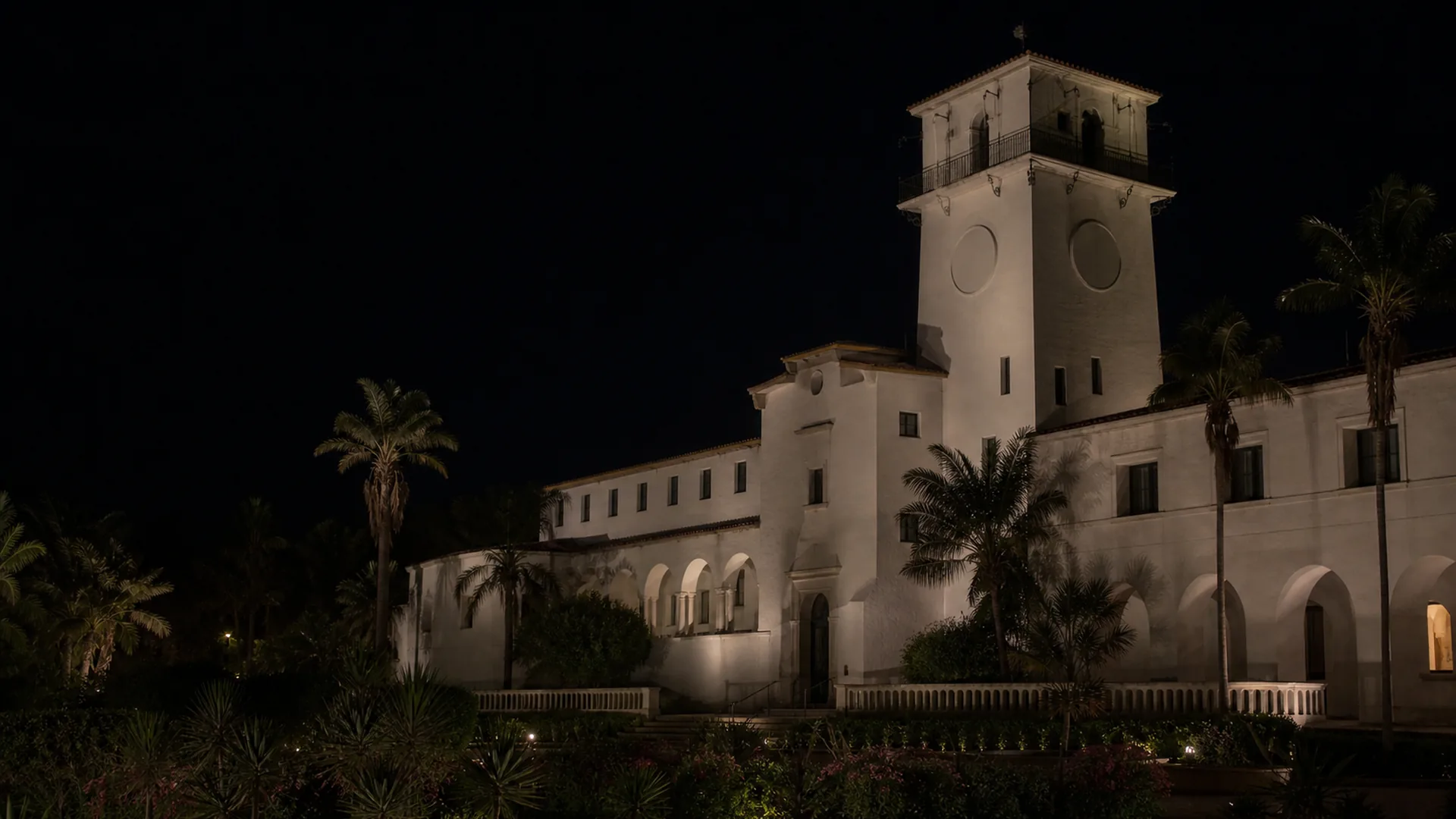 The Santa Barbara County Courthouse and its El Mirador tower rise above the Sunken Garden at night.